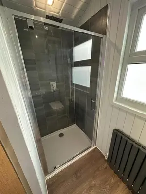 a shower with a glass door in a bathroom at The Stag's Head - Shepherds Hut in Great Singleton