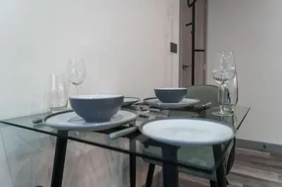 a glass table with two bowls and wine glasses on it at Lovely 1 Bedroom Apartment in Preston in Preston
