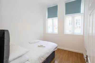 a white room with a bed and two windows at Central Liverpool L1 in Liverpool