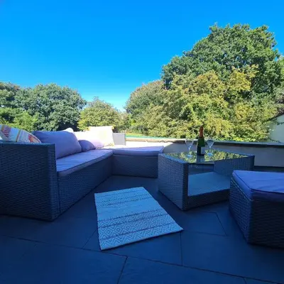 a patio with couches and a table and trees at The Coach House in Blackpool