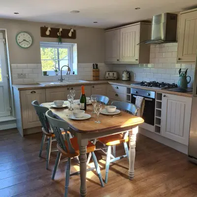 a kitchen with a wooden table with chairs and a sink at The Coach House in Blackpool