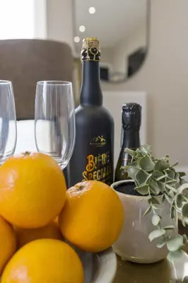 a table with two glasses and oranges and a bottle of wine at The Park Road Suites by Central Beach Leisure in Blackpool