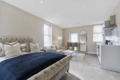 a bedroom with a large bed and a kitchen at The Park Road Suites by Central Beach Leisure in Blackpool