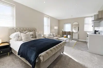 a bedroom with a large bed and a kitchen at The Park Road Suites by Central Beach Leisure in Blackpool