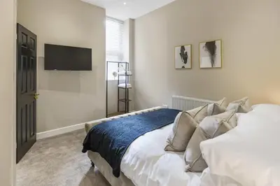 a bedroom with a bed and a flat screen tv at The Park Road Suites by Central Beach Leisure in Blackpool