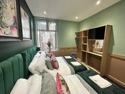a green room with two beds and a television at Strawberry Fields Suite by Sasco Apartments in Blackpool