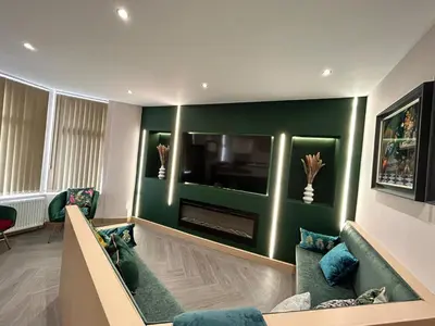 a living room with a green wall with a flat screen tv at Strawberry Fields Suite by Sasco Apartments in Blackpool
