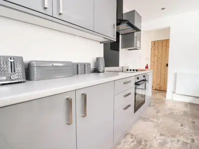 a kitchen with white cabinets and stainless steel appliances at Anandom in Blackpool