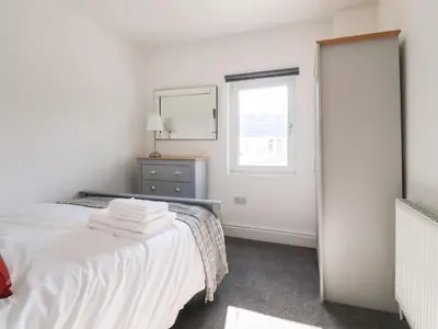 a white bedroom with a bed and a mirror at Anandom in Blackpool