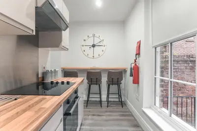 a kitchen with a counter and a clock on the wall at Clarence Street Town House in Liverpool