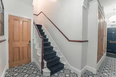 a hallway with a staircase and a wooden door at Clarence Street Town House in Liverpool