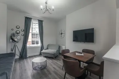 a living room with a couch and a table and a tv at Clarence Street Town House in Liverpool
