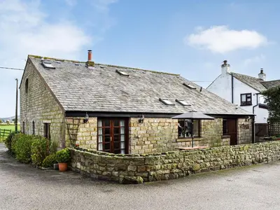a stone building with an umbrella in front of it at Priory Barn in Burscough