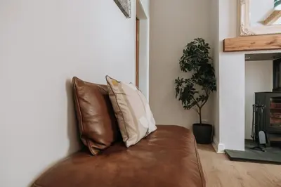 a brown leather couch with two pillows on it at Church View Cottage in Whalley