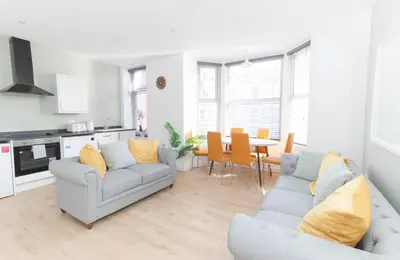 a white living room with two couches and a table at No 10 Apartments in Blackpool