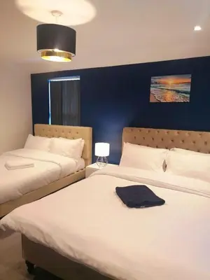two beds in a bedroom with a blue wall at No 10 Apartments in Blackpool