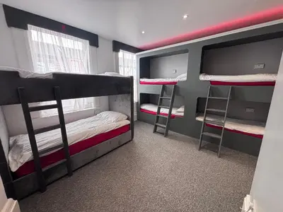 a room with three bunk beds and two windows at The Breckfield Hotel in Liverpool