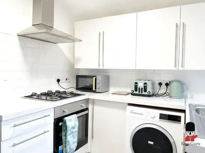 a white kitchen with a stove and a washer and dryer at KozyGuru / Wigan / 2BR 4Beds / Newly Refurbished Stylish Holiday House / Close to Big Retail Park / UWNE034 in Wigan