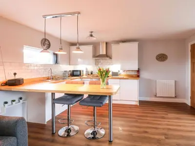 a kitchen with a wooden table and two bar stools at Meols Holiday Lodge in Wirral