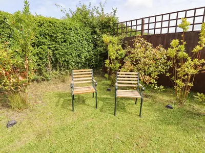two chairs sitting in the grass in a yard at Meols Holiday Lodge in Wirral