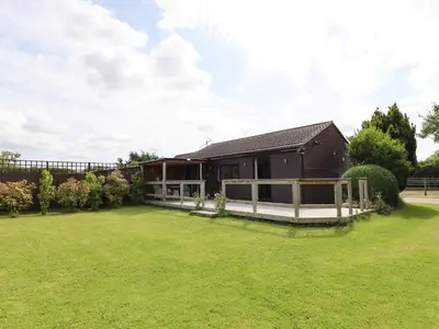 a house with a large lawn in front of it at Meols Holiday Lodge in Wirral