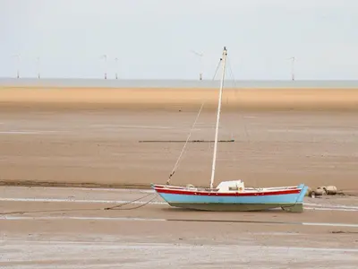 a boat sitting on the sand on a beach at Meols Holiday Lodge in Wirral