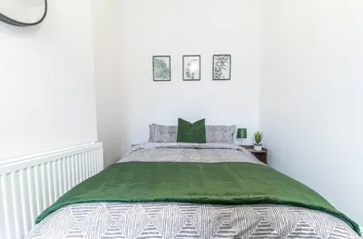 a bedroom with a bed with a green blanket at 24 Baden Powell in Barrow in Furness