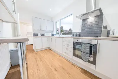 a kitchen with white cabinets and a large window at 24 Baden Powell in Barrow in Furness