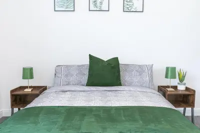 a bedroom with a bed with green sheets and two lamps at 24 Baden Powell in Barrow in Furness