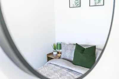 a mirror reflection of a bed with green pillows at 24 Baden Powell in Barrow in Furness