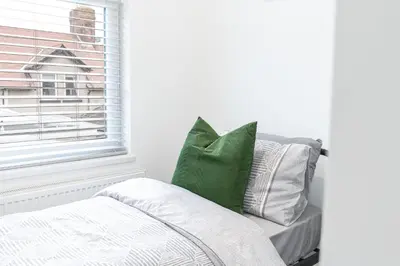 a bed with green and white pillows next to a window at 24 Baden Powell in Barrow in Furness