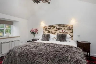 a bedroom with a large bed with a large blanket at Finest Retreats - Middle Warble Stables in Mellor