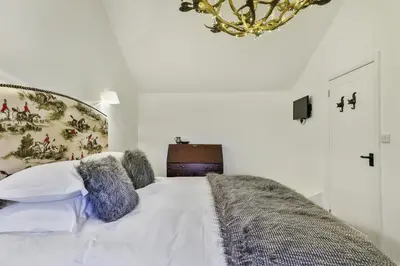 a bedroom with a large white bed with a chandelier at Finest Retreats - Middle Warble Stables in Mellor