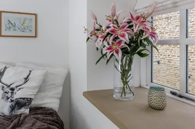 a vase with pink flowers on a table next to a window at Finest Retreats - Middle Warble Stables in Mellor