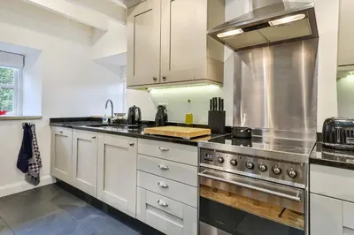 a kitchen with white cabinets and a stove top oven at Finest Retreats - Middle Warble Stables in Mellor