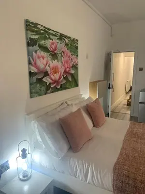 a bedroom with a white bed with a painting on the wall at Bloomsbury House - Modern studios near Anfield in Liverpool