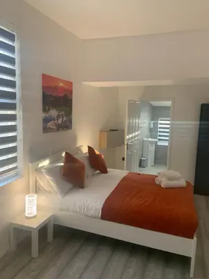 a bedroom with a large bed with orange and white sheets at Bloomsbury House - Modern studios near Anfield in Liverpool