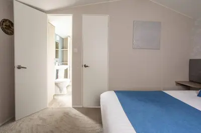a white bedroom with a bed and a bathroom at Borwick Lakes Holiday Caravan (Partial Lake View) in Borwick