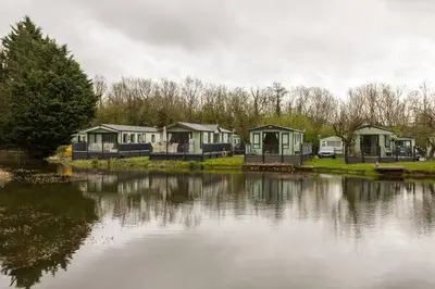 a row of houses next to a body of water at Borwick Lakes Holiday Caravan (Partial Lake View) in Borwick