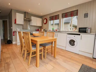 a kitchen with a table and chairs and a washing machine at Holly Lodge in Preston