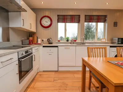 a kitchen with a table and a clock on the wall at Holly Lodge in Preston