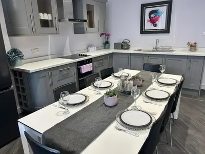 a kitchen with a table with plates and wine glasses at Sugar Hill Suite by Sasco Apartments in Blackpool