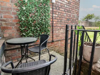 a patio with two chairs and a table and a brick wall at Ismay Billiard Room Apartment - Titanic Interest in Crosby