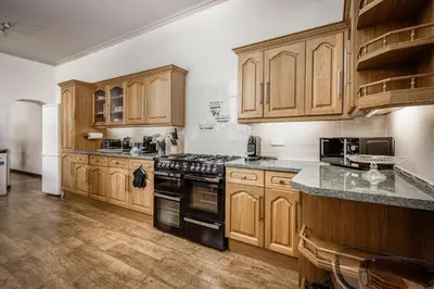 a kitchen with wooden cabinets and a black stove top oven at Bentinck Residence by Sasco Apartments, Lytham St Annes in Lytham St Annes