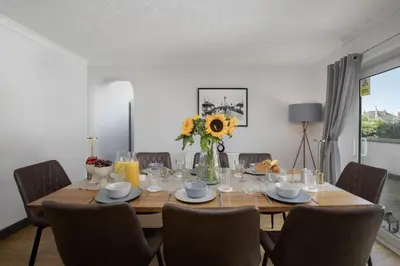 a dining room table with chairs and a vase of flowers at Bentinck Residence by Sasco Apartments, Lytham St Annes in Lytham St Annes