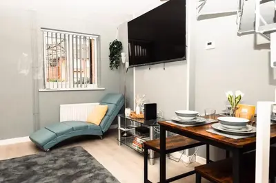 a living room with a blue couch and a table at Elegant 2 bed with hot tub and a host of amenities in Liverpool