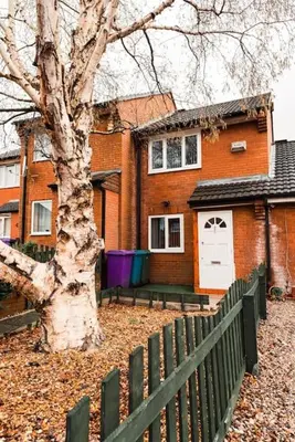 a house with a fence and a tree in front of it at Elegant 2 bed with hot tub and a host of amenities in Liverpool