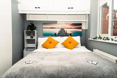 a bedroom with a large bed with orange pillows at Elegant 2 bed with hot tub and a host of amenities in Liverpool