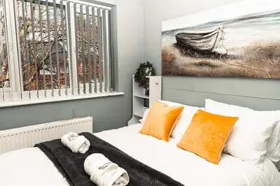 a bedroom with a bed with orange pillows and a painting at Elegant 2 bed with hot tub and a host of amenities in Liverpool