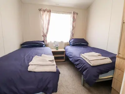 two beds in a room with purple sheets and a window at Rosella 38 in Morecambe